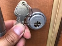 YANAIのRシリンダーへ交換。ドアに取り付けたシリンダーの前で付属の鍵をもっている