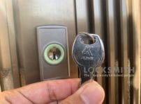 鍵交換完了。取り付けた錠前の前で鍵をもっている