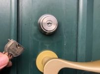 MIWAのシリンダーへ交換しました。扉の前で付属の鍵３本を持っている