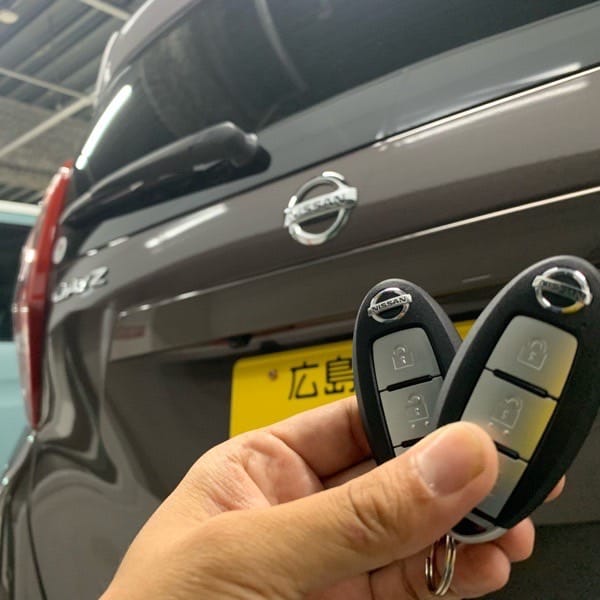 ラグビーボール状の既存のスマートキーと新たに作製したスペアキーを手に持っている