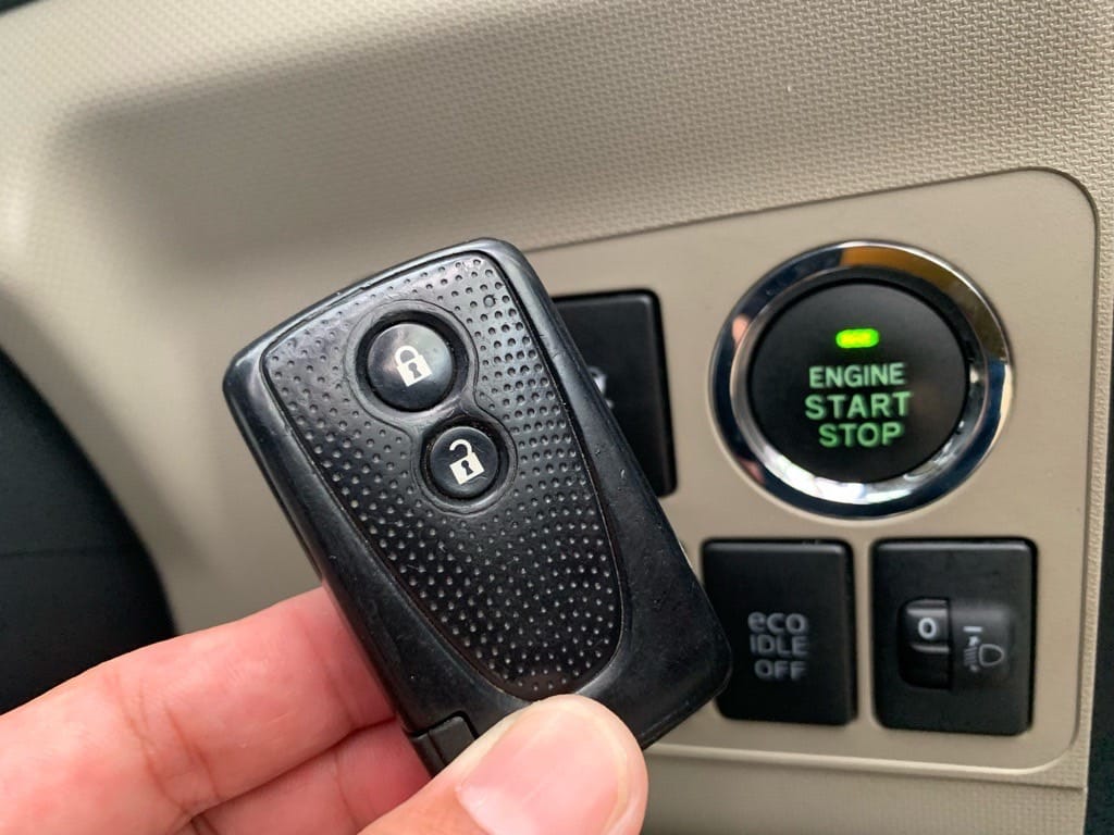 登録が完了したダイハツムーヴのスマートキーをスタートボタンの前で持っている