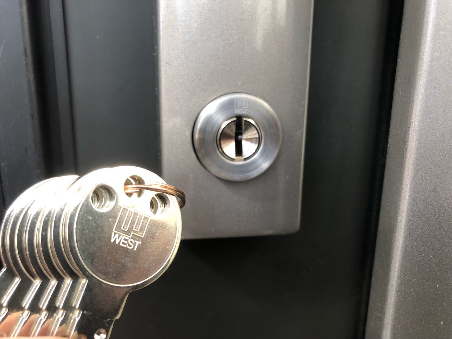 勝手口の鍵交換、付属の鍵をシリンダーの前で持っている