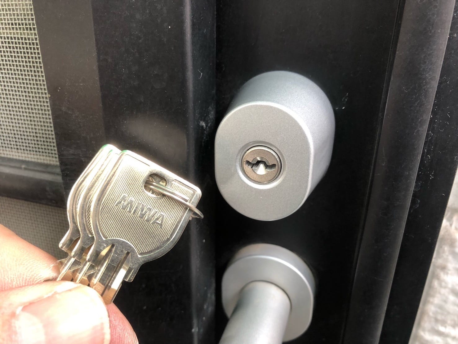 付属の鍵を玄関ドアについているシリンダーの前で持っている