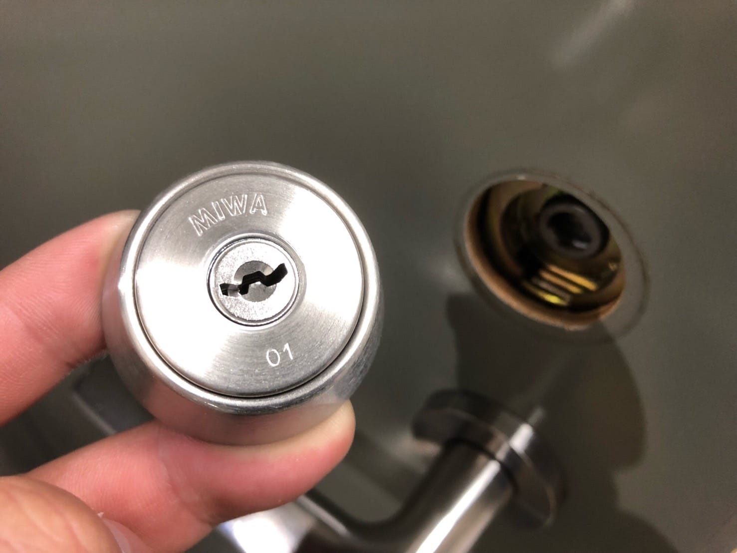 同メーカーのシリンダーを手で持っている。こちらに交換していきます