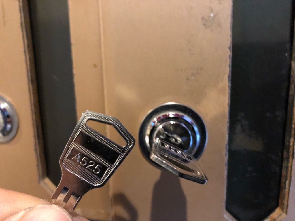 マンションの集合ポストの鍵を作ってポストの前で鍵を持っている