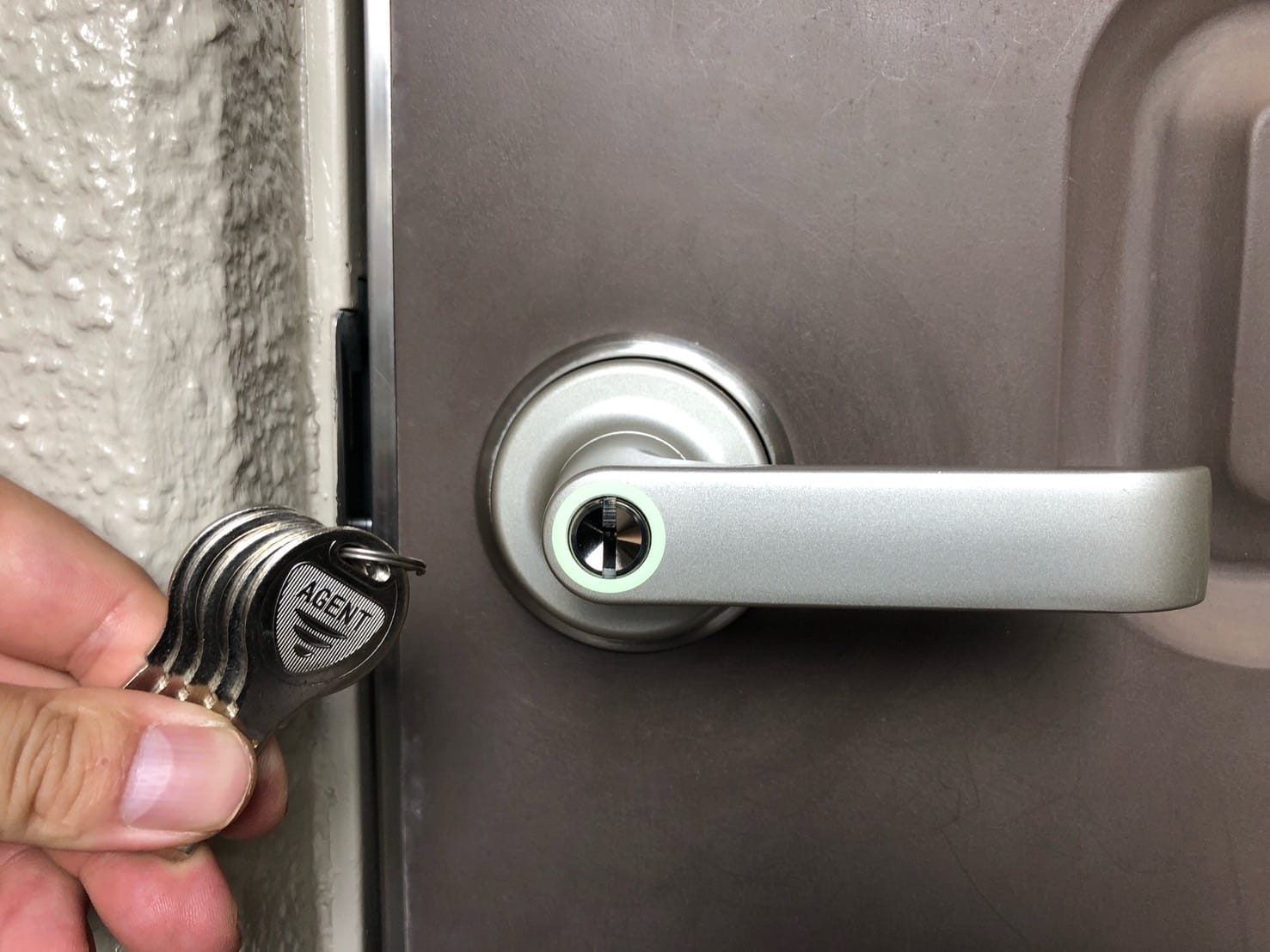 レバーハンドルタイプへ交換した玄関ドアと付属の鍵を手に持っている
