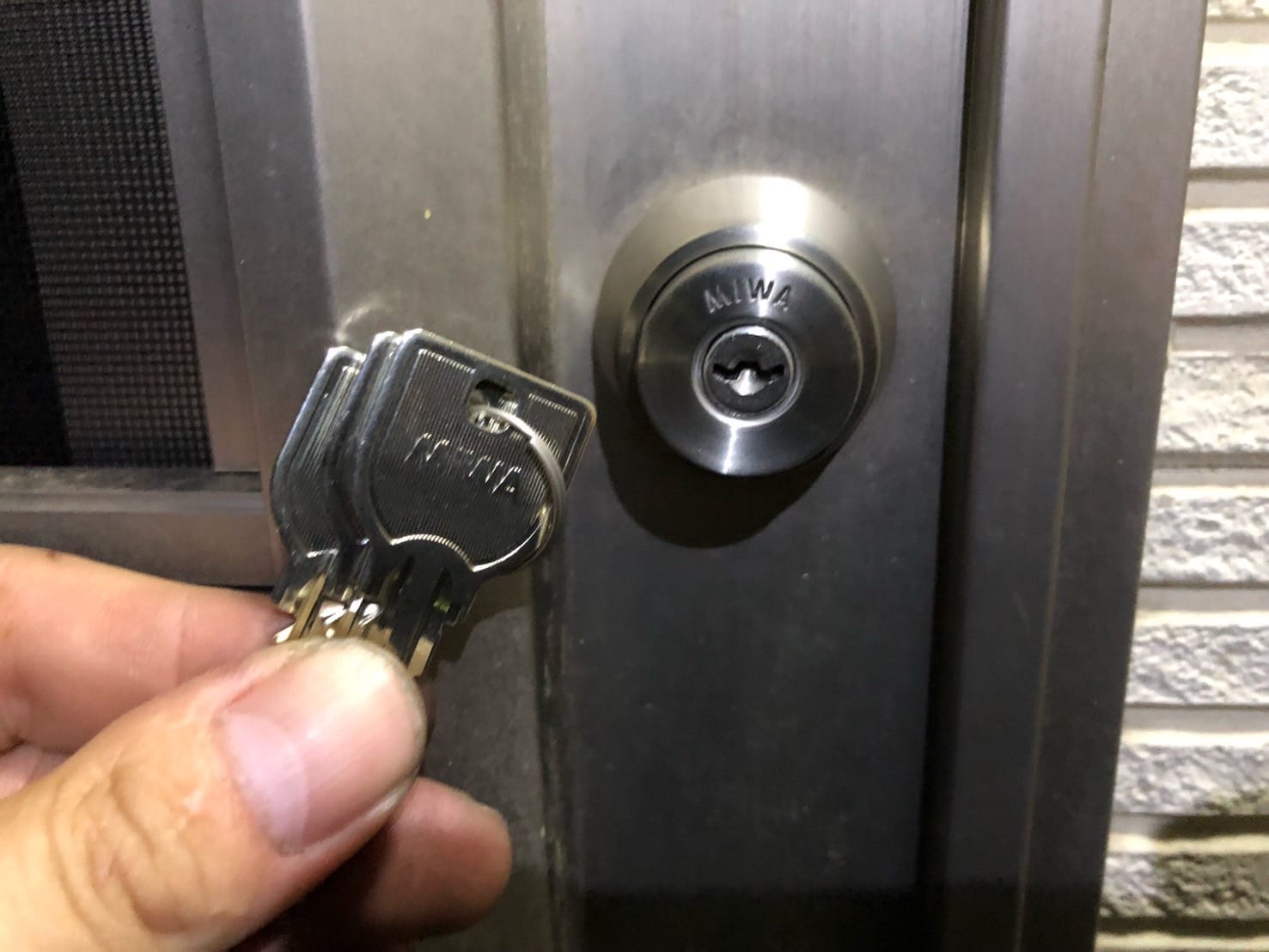 扉に取り付けたU9シリンダー、付属の鍵を手に持っている