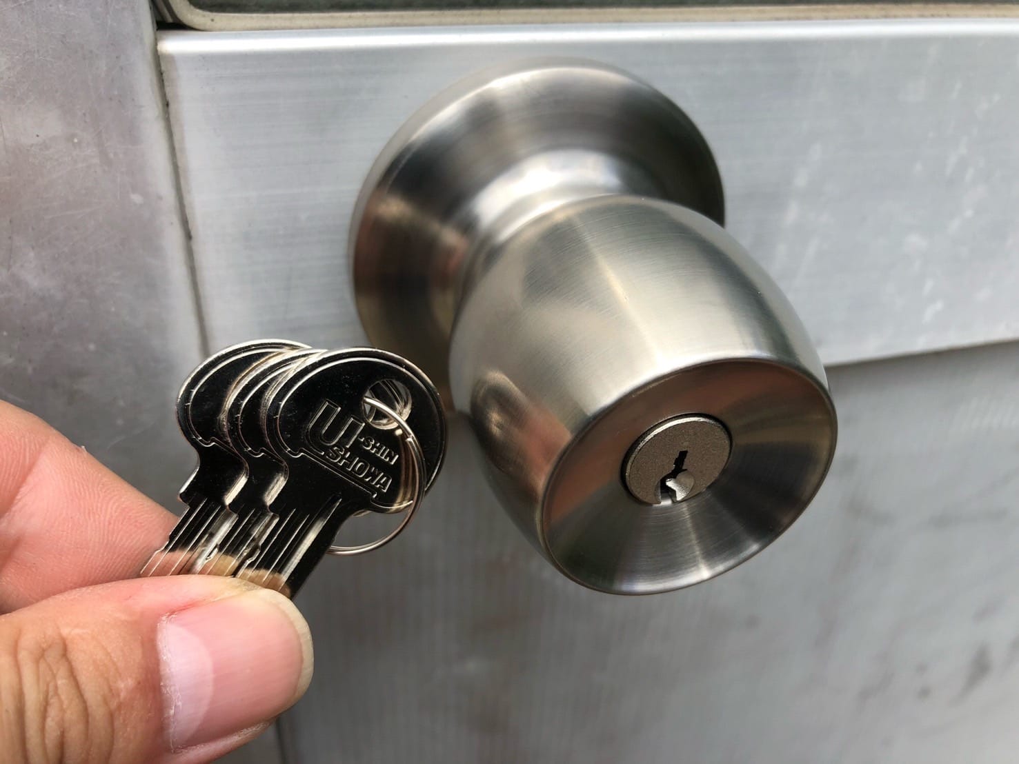 新しく取り付けた握り玉の横で付属の鍵を持っている