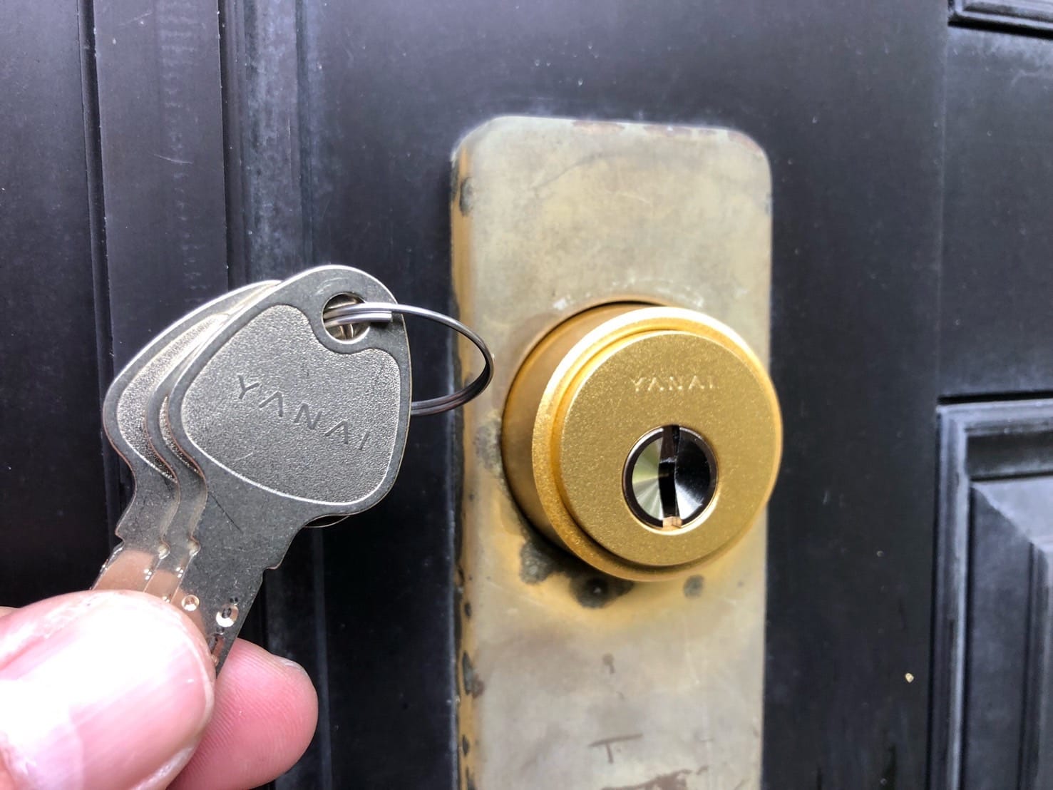 新しく取り付けたRシリンダーの前でディンプルキーを持っている