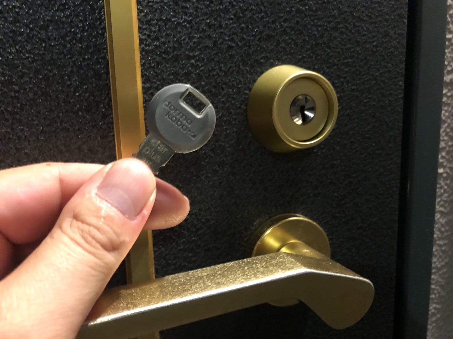 鍵交換を行った玄関ドアの前で鍵を持っている