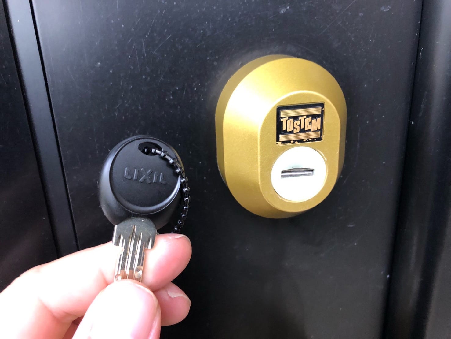 再びドアに取り付けたシリンダーの前で鍵を持っている
