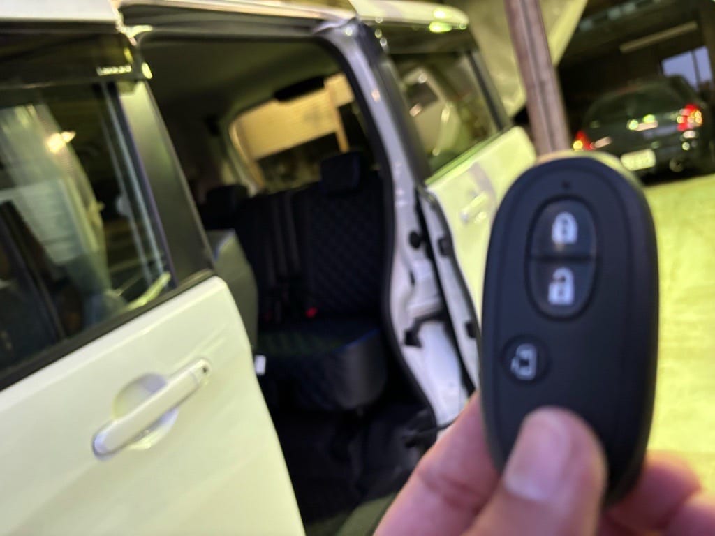 パワースライドドアが開いたソリオの前で登録が完了したスマートキーを手に持っている