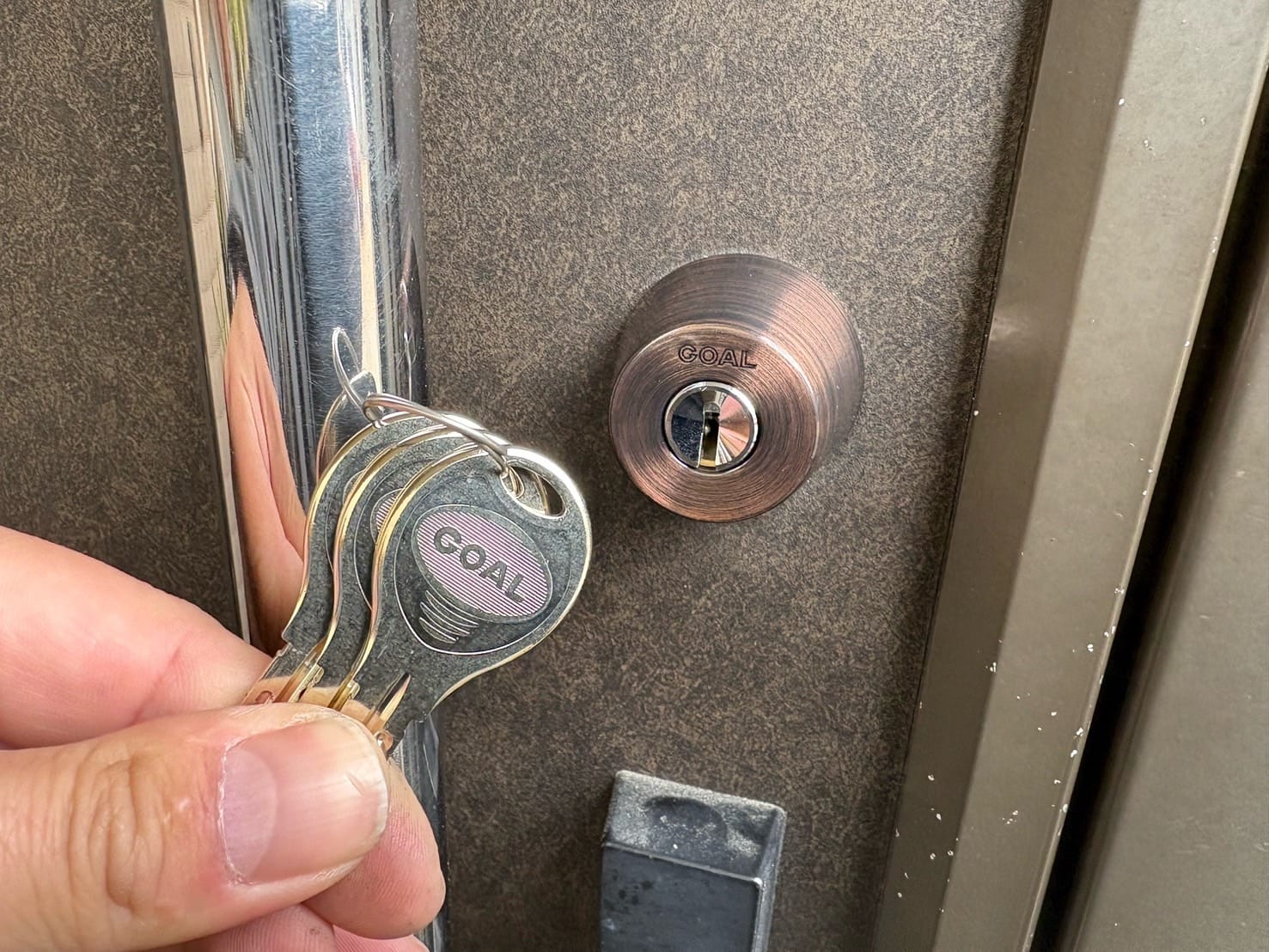 鍵交換完了。シリンダーの近くで付属の鍵を持っている