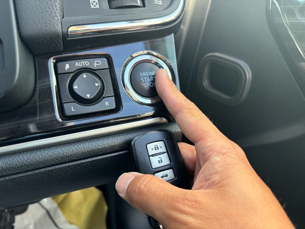 クラウンのスマートキーを持ってスタートボタンを押している