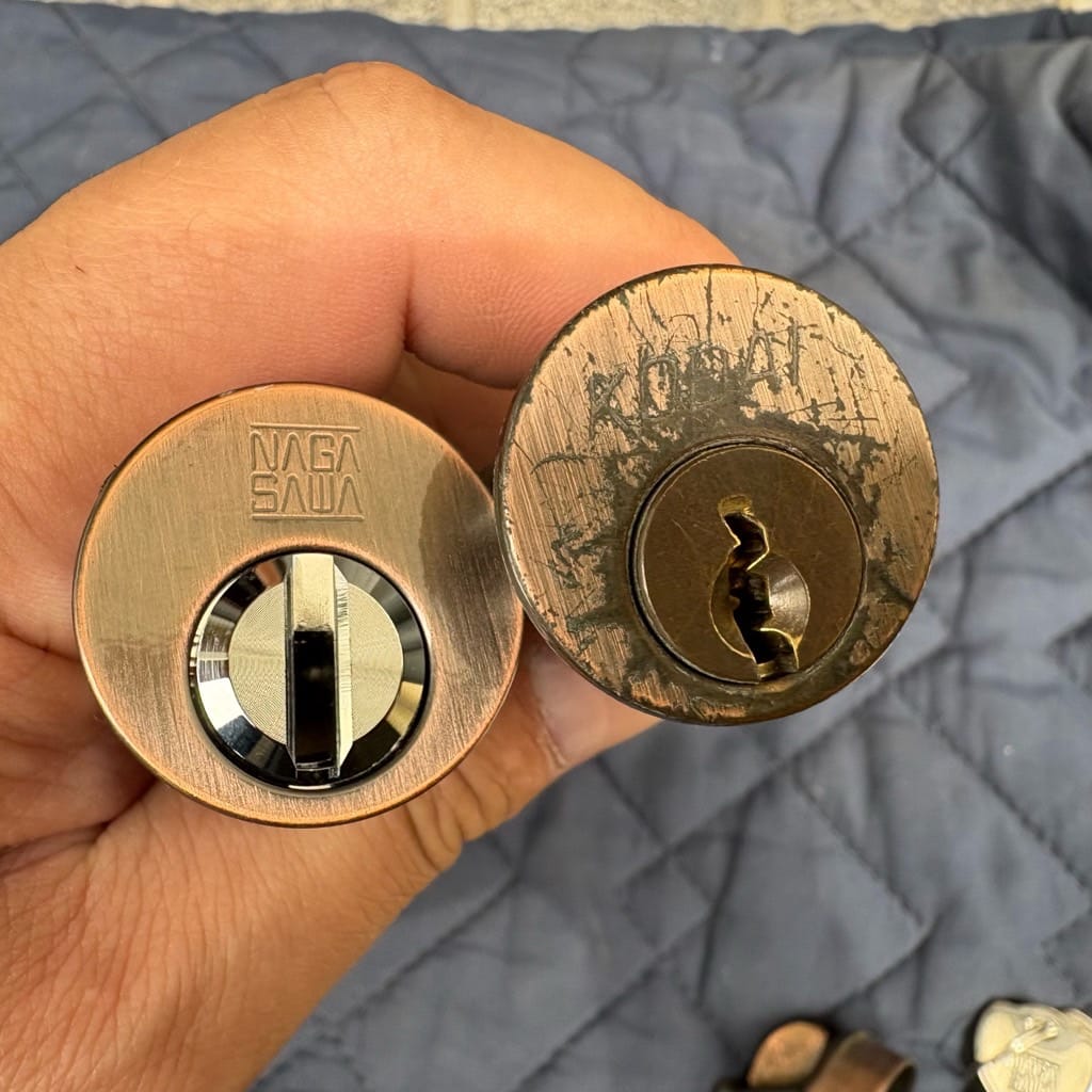 扉から外したシリンダーと交換予定のシリンダー