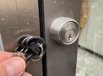 ドアに新しいキーシリンダーを取り付けて交換完了。付属の鍵をシリンダーの近くで持っている