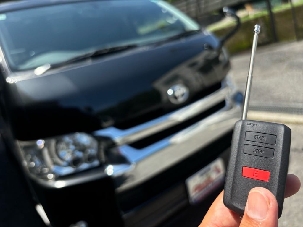 ハイエースの前でリモコンを持っている