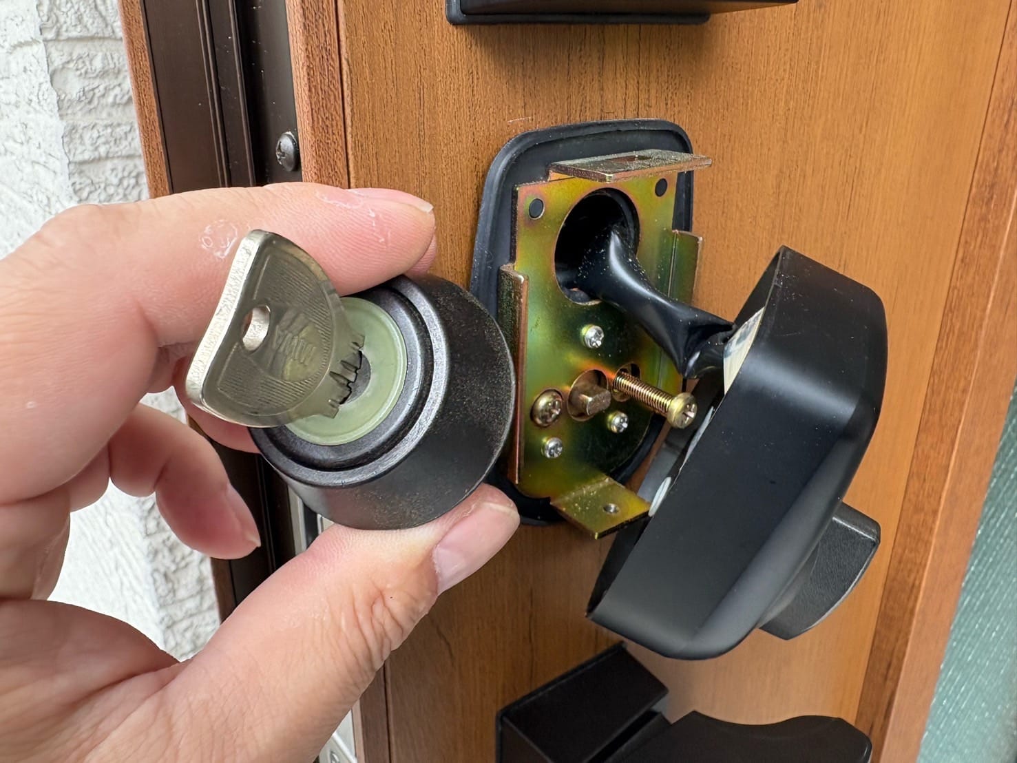 ドアから取り外したキーシリンダーを手に持っている