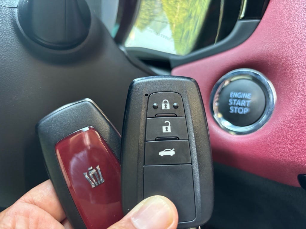 登録が完了したクラウンのスマートキーをスタートボタンの前で持っている