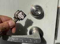 鍵交換完了。新しいキーシリンダーがついた扉の近くで付属の鍵を持っている