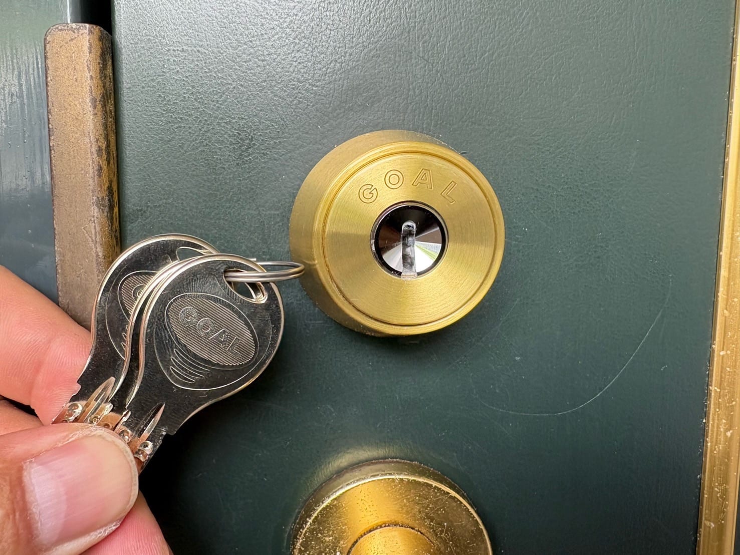 GOAL社のディンプルシリンダーへと交換完了　扉の近くで付属の鍵を持っている