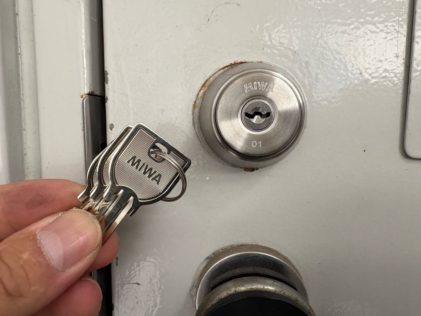 新しい鍵へ交換しました。付属の鍵を扉の前で持っている