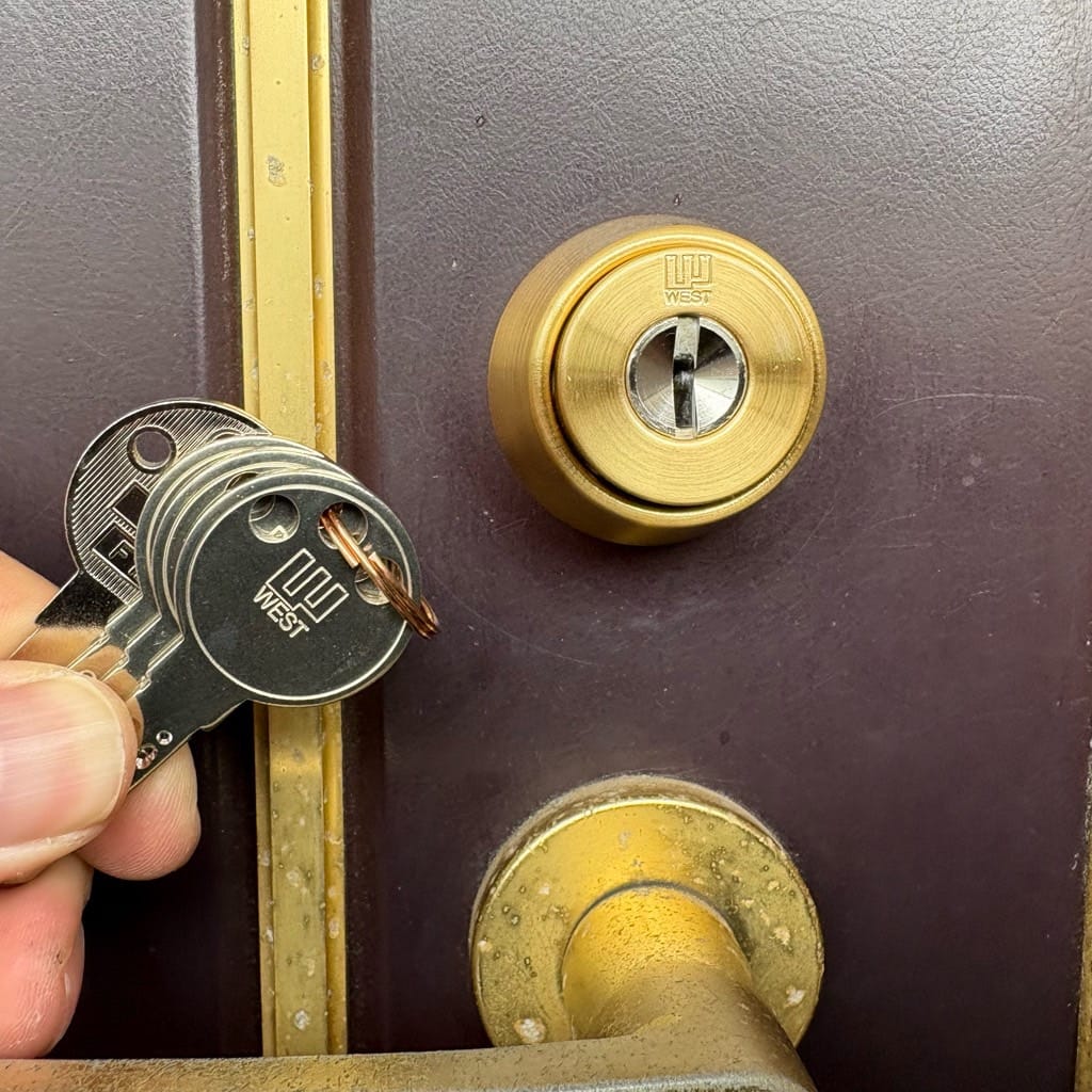 ディンプルシリンダーへ交換完了。付属の鍵数本を扉の近くで持っている