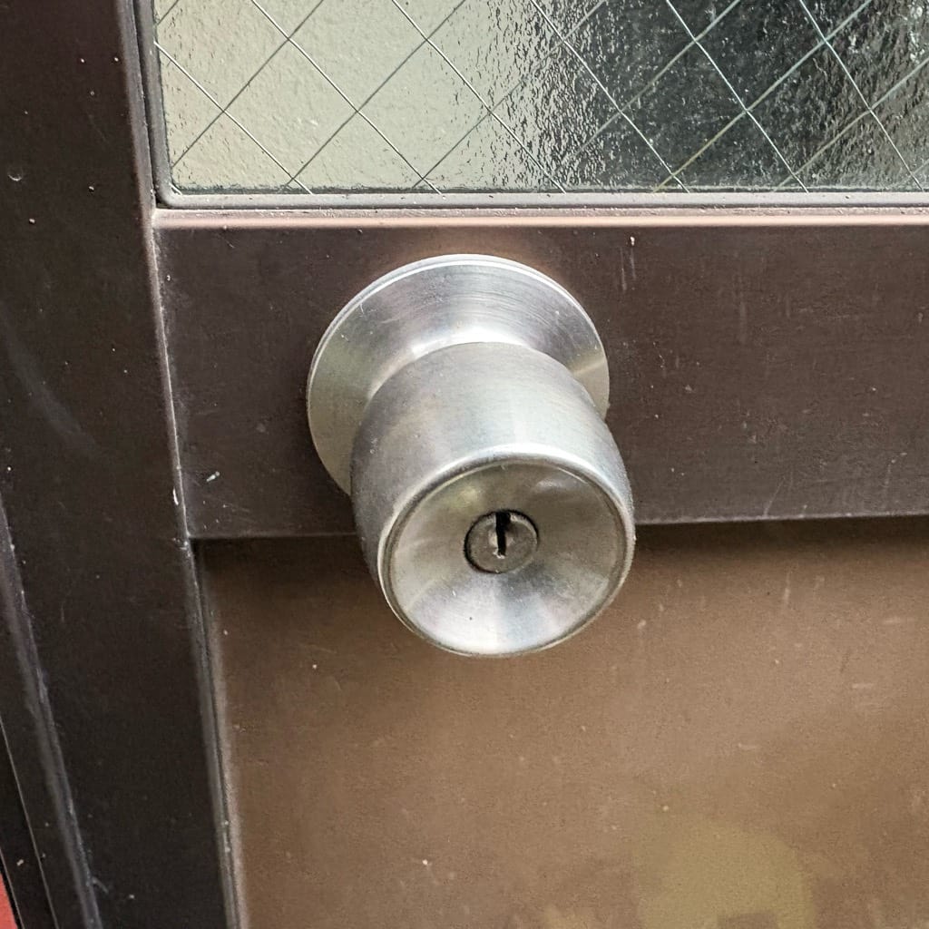 アルミサッシ扉には握り玉タイプのインテグラル錠が取り付けられている。こちらの鍵を解錠します