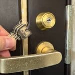 鍵交換完了。扉のシリンダー近くで付属の鍵を持っている