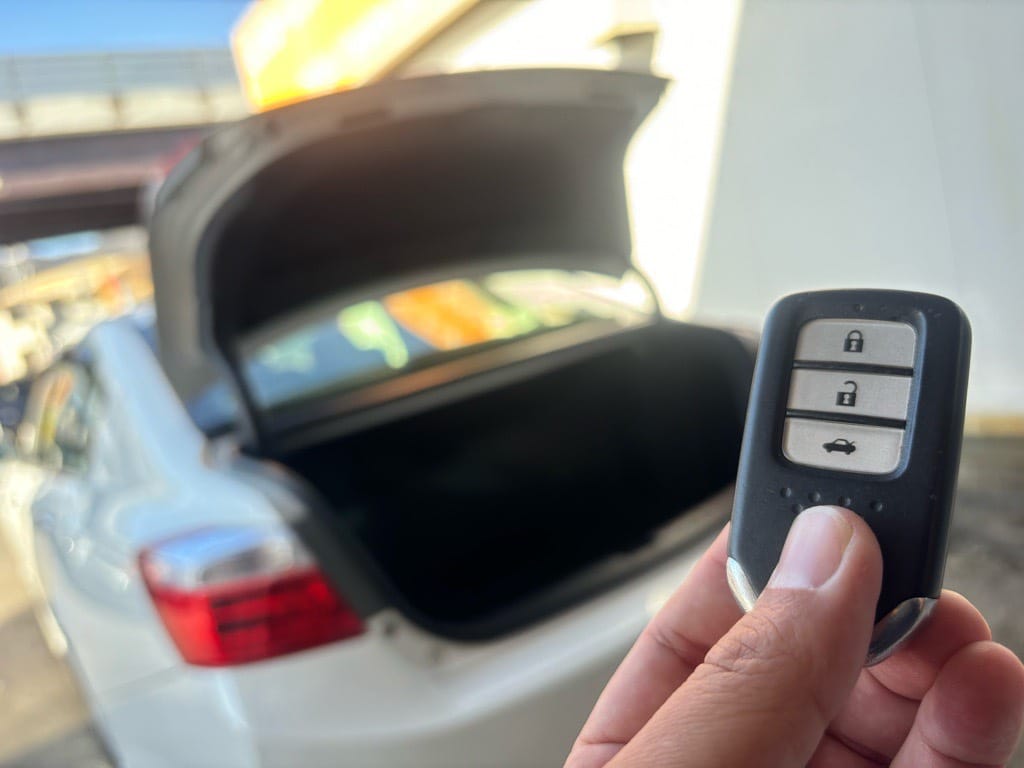 トランクが開いているアコードを背景にスマートキーを持っている